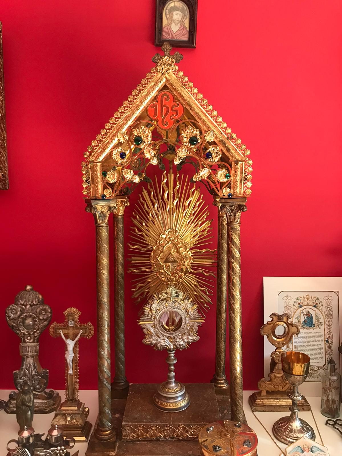 Tabernacolo dorato con reliquiari su parete rossa
